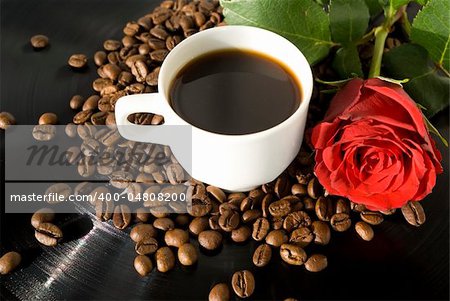 cup with coffee on grains of coffee with rose