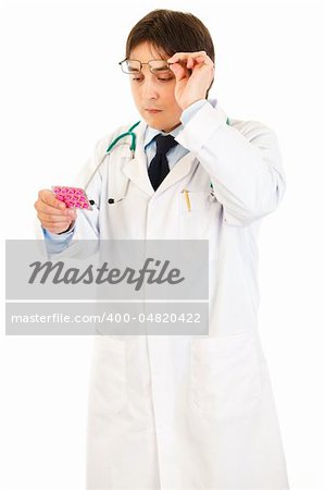 Concentrated doctor raising eyeglasses and reading name of drug  isolated on white