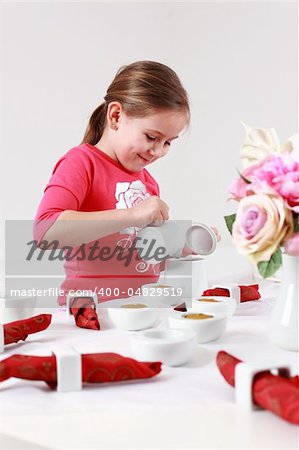 Girl helps to set the table - pouring tea