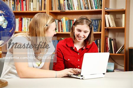 Teen girls using the computer in the school library.