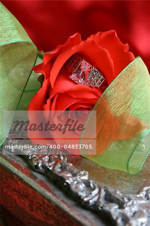 Engagement ring inside a red rose with green organza ribbon