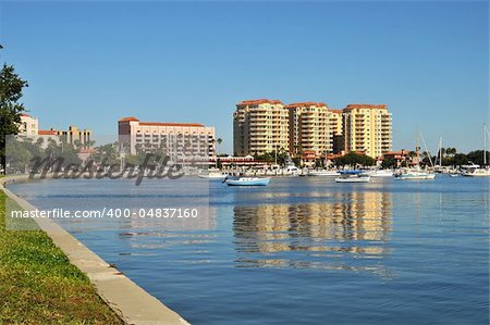 Condos and apartments on the shoreline of a Florida inlet. Boats and yachts appear in the foreground amidst the serene reflections of the buildings this peaceful morning.