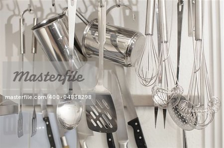 Rack of kitchen utensils isolated on white. Stainless steel