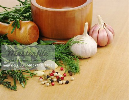 Mortar with garlic, peppercorns, dill, rosemary and thyme on wooden board (Selective Focus)