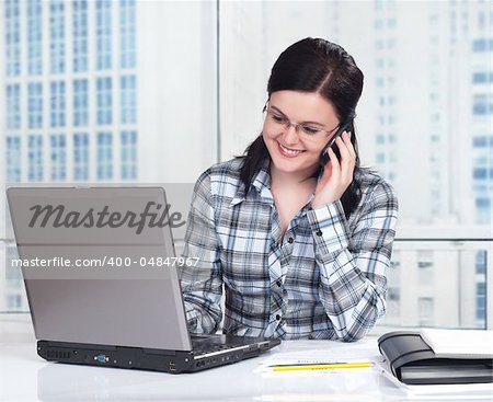 Portrait of a pretty young woman with phone in front of a laptop computer