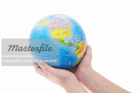 Young boy's hand holding completed globe jigsaw puzzle on white background