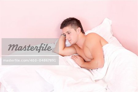 Sad man lying in double bed, looking on the empty seat