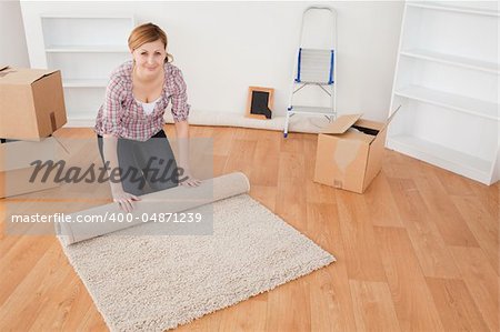 Attractive woman rolling up a carpet to prepare to move house