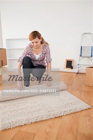 Pretty woman rolling up a carpet to prepare to move house