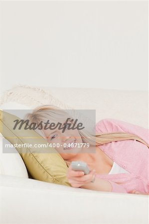 Attractive blonde woman posing while lying on a sofa in the living room