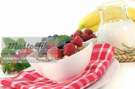 Cereal bowl of fresh fruit, nuts and milk before a white background