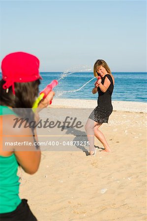 Girls with water pistols fooling around on the beach