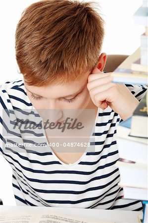 Teen boy learning at the desk, isolated on white