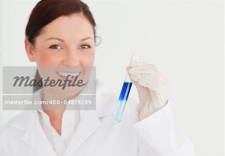 Smiling scientist looking at the camera while holding a  test tube in a lab