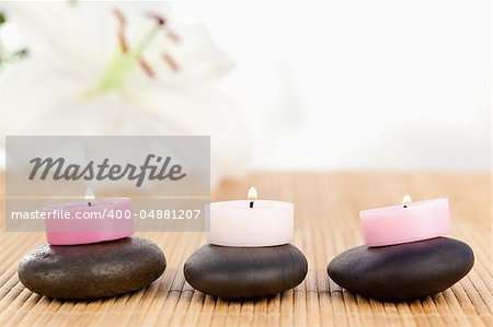 Lighted candles on black pebbles