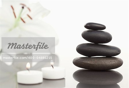 White orchid with lighted white candles and a black pebble stack the camera focus on the object