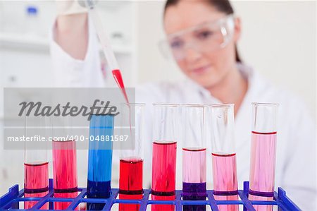 Attractive red-haired scientist filling up a test tube in a lab