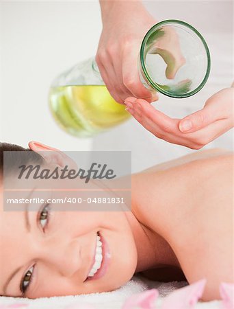 Portrait of a smilling woman getting massage oil on her back in a spa