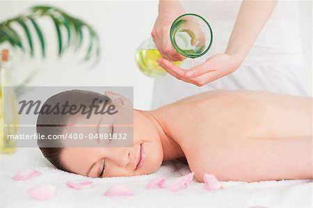 A woman eyes closed getting massage oil on her back in a spa