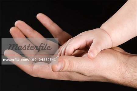 Men's and children's hand isolated on black background