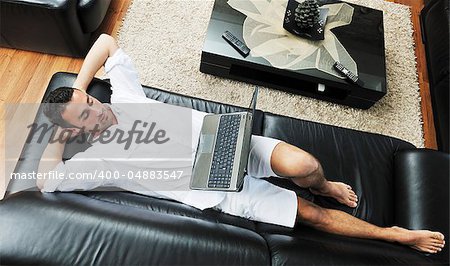 Portrait of a relaxed young guy using laptop at home indoor