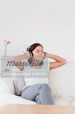 Delighted dark-haired woman listening to music in her living room