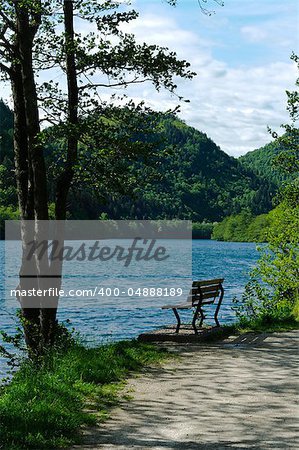 A solitary wooden bench facing the calm waters of a beautiful Alpine lake