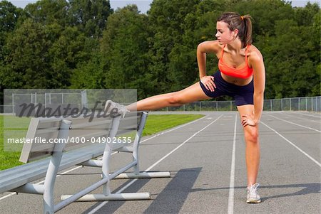 An athletic teenager stretching before exercising on a track outdoors