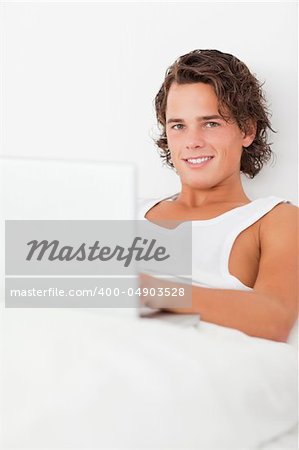 Man using a notebook in his bedroom