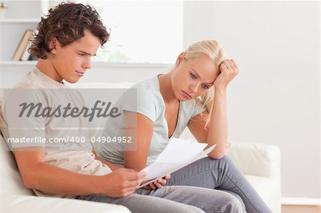 Worried couple reading letters in the living room