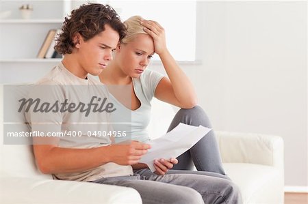 Unhappy couple holding an invoice in the living room