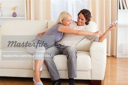 Smiling couple fighting for the remote in their living room