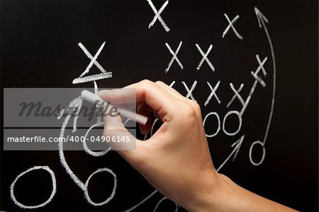 Man drawing a game strategy with white chalk on a blackboard.