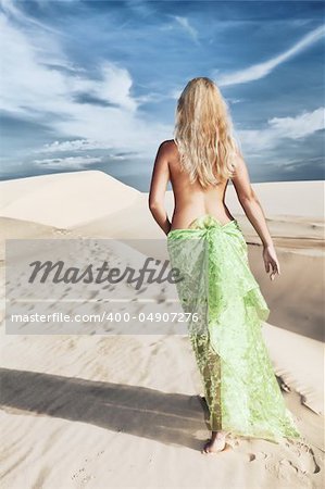 Woman walking among desert dunes at day time