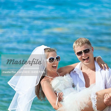 Groom holding up a bride on the beach