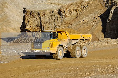 A yellow dump truck is driving in a mine
