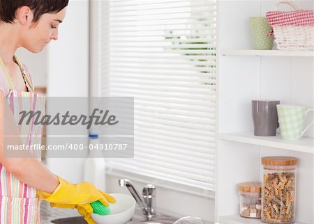Beautiful woman washing the dishes in the kitchen