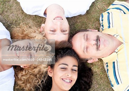Happy family of four on green grass.