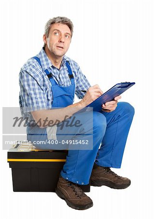 Confident service man sitting on toolbox and taking notes. Isolated on white