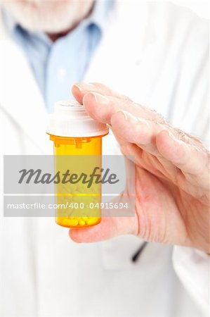 Closeup of a pharmacist's hands holding a bottle of prescription pills.