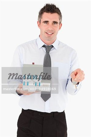 Businessman holding a key and a miniature house against a white background