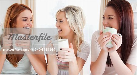 Young Women sitting at a table with cups in a kitchen