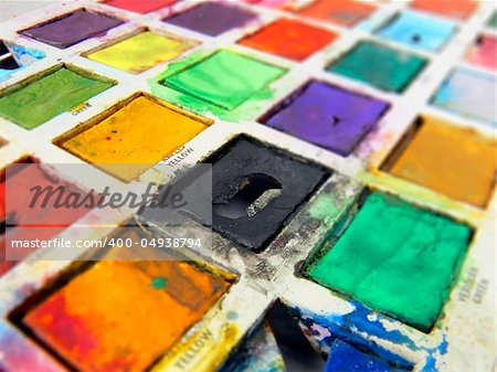 closeup of child's old tin toy paintbox with the brilliant colours of childhood; wideangle view; differential focus