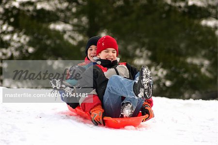 Two Boys smiling happy having a good time sledding