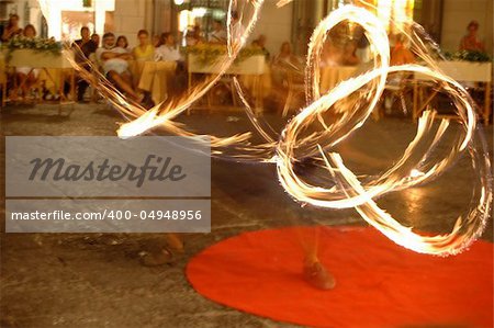Fire dancers perform in the street to crowds of tourists.