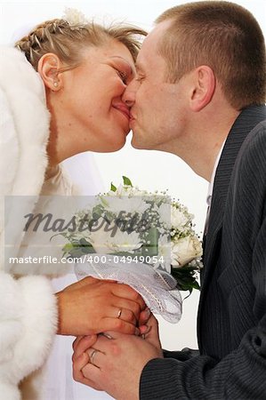 newlywed bride and groom kissing and holding flowers