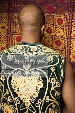 Rear view portrait of African-American mid-adult man wearing embroidered African vest.