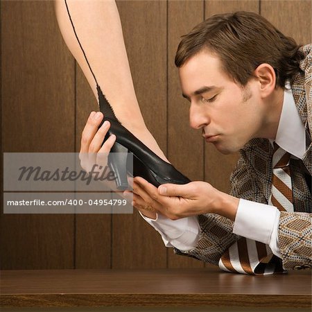 Mid-adult Caucasian male holding Caucasian female shoe and preparing to kiss it.