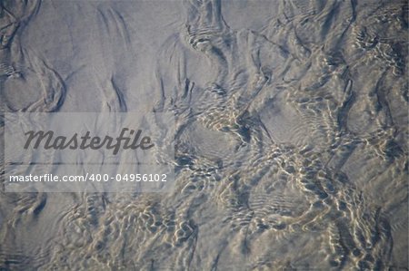 Shallow pristine sea water rippling over beach sand