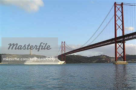 Cruise ship under Ponte 25 de Abril bridge in Lisbon with a view of Cristo Rei